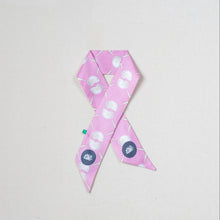Load image into Gallery viewer, A pink satin awareness ribbon pin with a white seashell pattern, featuring a navy blue circular medallion with a white lotus flower on each tail, set against a plain off-white background.