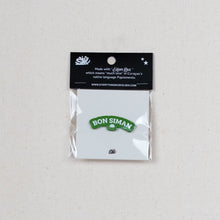 Load image into Gallery viewer, A small Bon Siman enamel pin in its original packaging, featuring a green and white pin with the Bon Siman logo, sealed in a clear plastic bag with a black header card, set against a light textured background.
