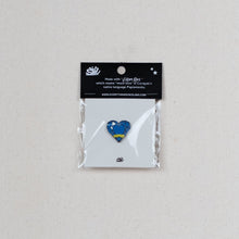 Load image into Gallery viewer, A small heart-shaped enamel pin with a blue and yellow landscape design is displayed on its original packaging, which includes a black header card with white text.
