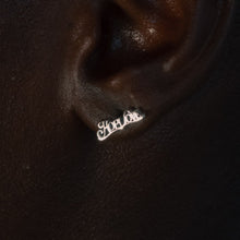 Load image into Gallery viewer, A close-up of a person's ear wearing a small silver script earring that reads 'Love'.
